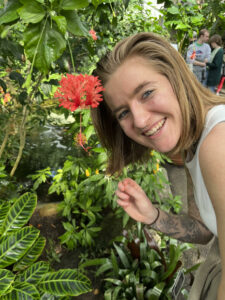 Photo of student Zoe Barany in front of greenhouse plants